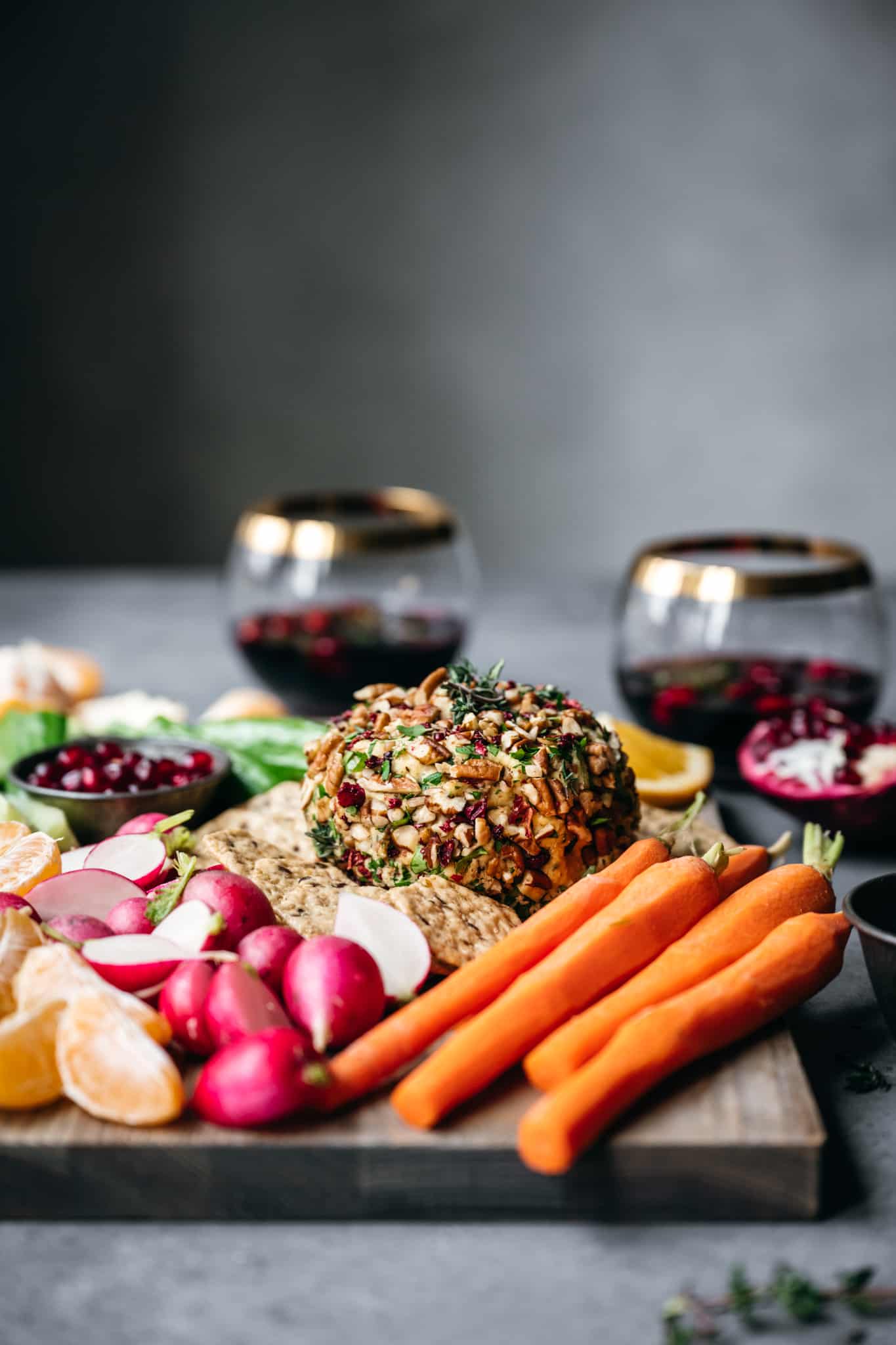 side view of vegan cheese ball with pecan coating on platter with crudites