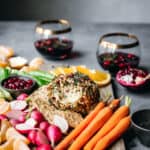 Cheese ball on a board with veggies and wine.