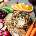 45 degree overhead of vegan cheeseball with nutty coating on a snack board with fresh vegetables