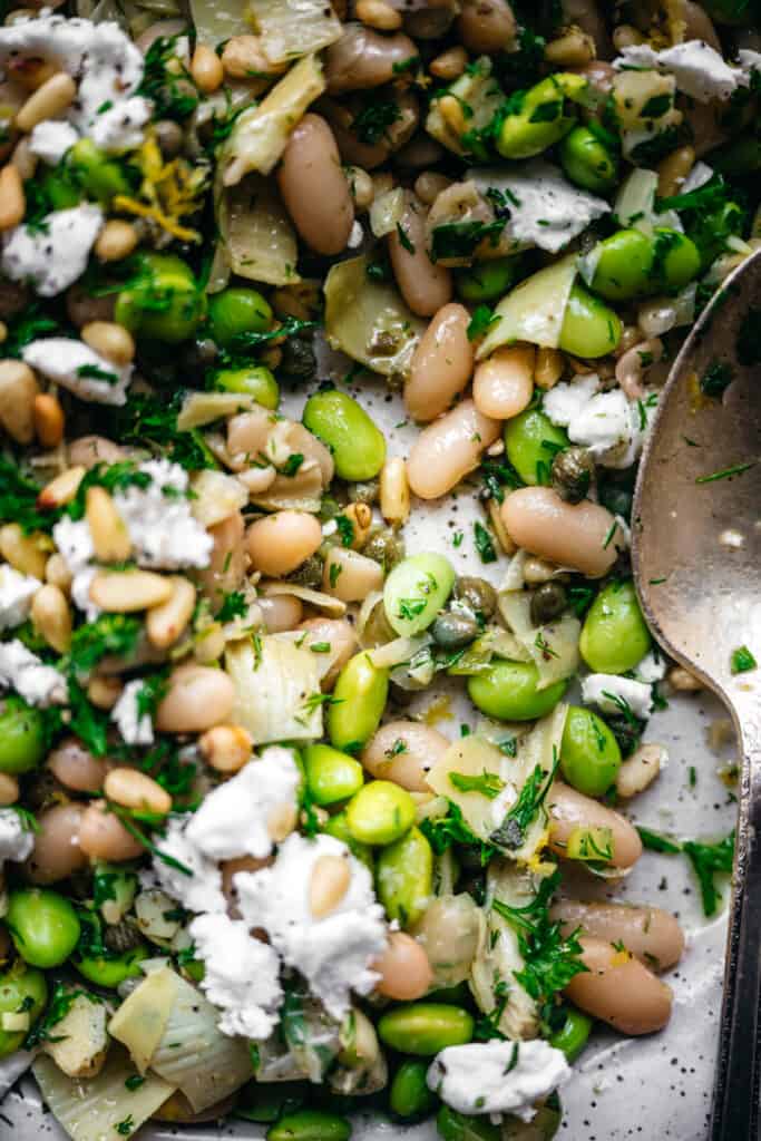 close up view of white bean and edamame salad with artichokes, capers, feta and pine nuts
