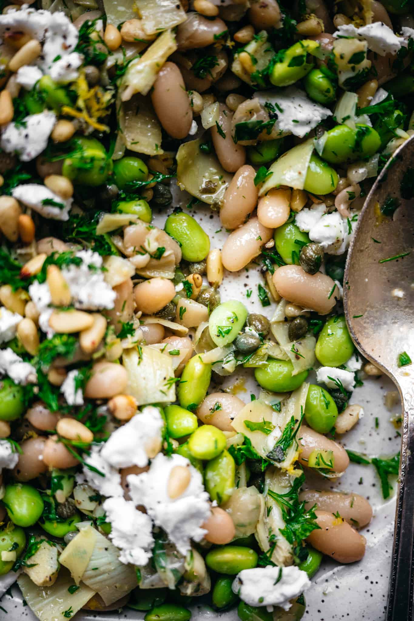 close up view of white bean and edamame salad with artichokes, capers, feta and pine nuts