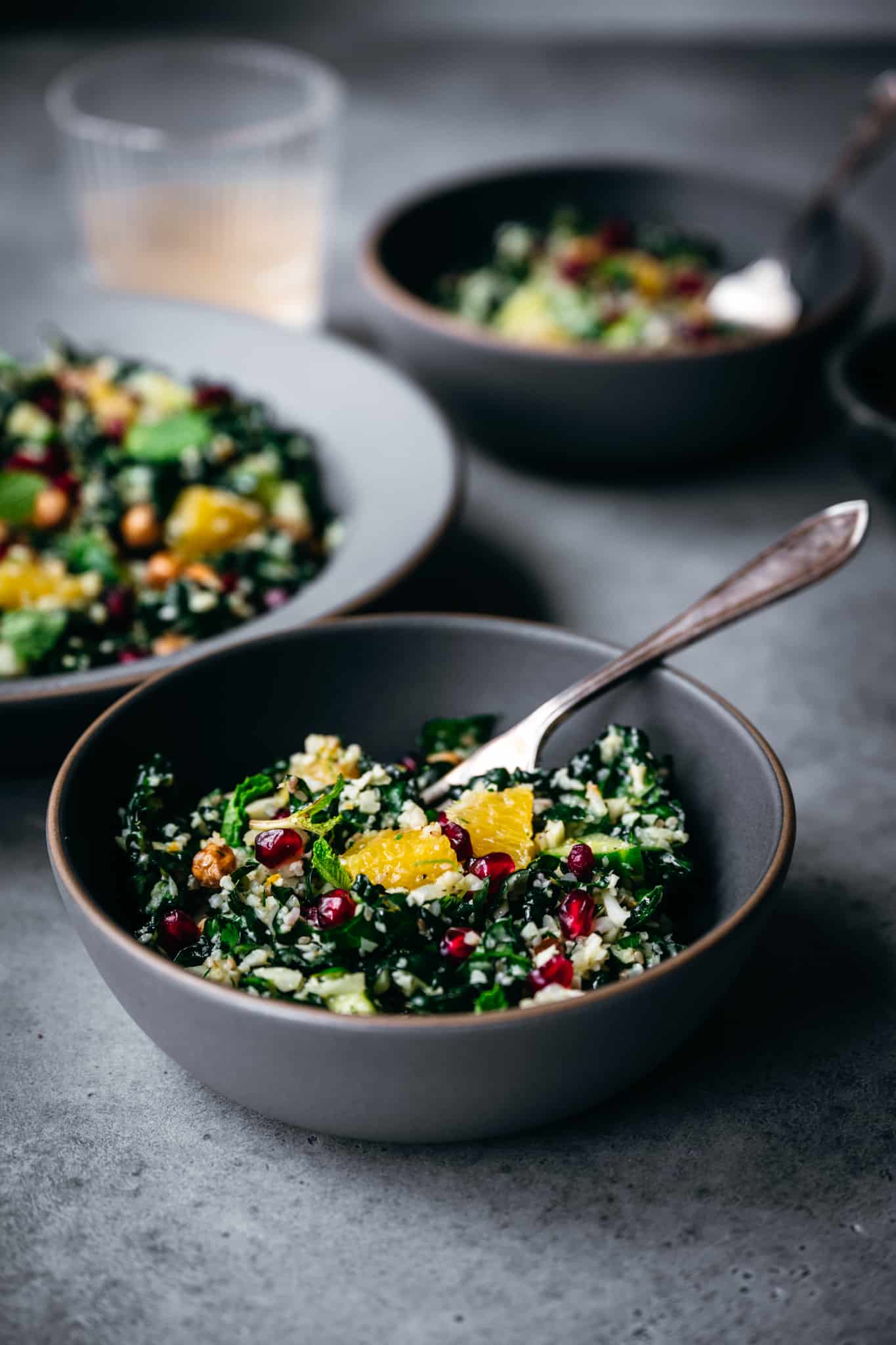 side view of bowl of cauliflower rice and kale salad with oranges and pomegranate