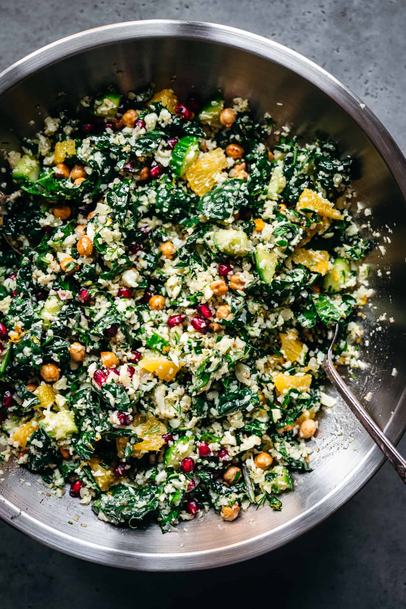 overhead view of cauliflower vegetable salad in a mixing bowl with spoon