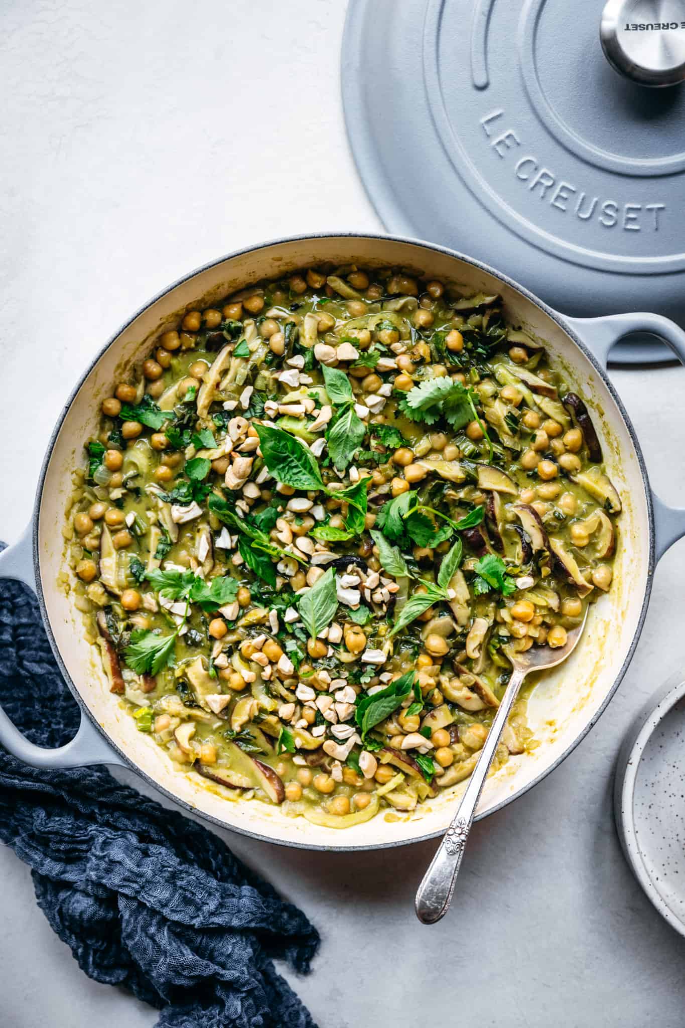 overhead view of vegan green curry with chickpeas and mushrooms in Le Creuset braiser