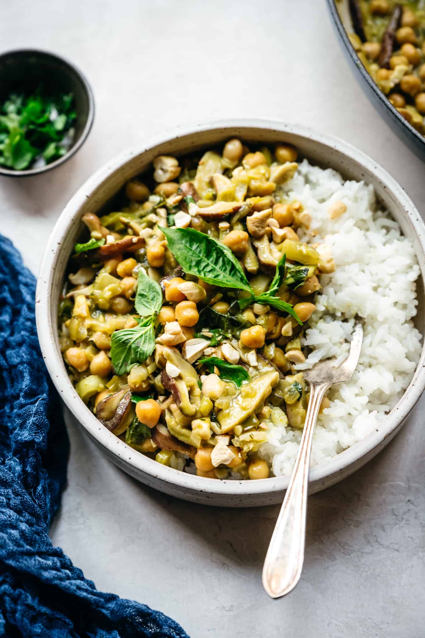 vegan green curry with chickpeas and mushrooms served over white rice in bowl with fork