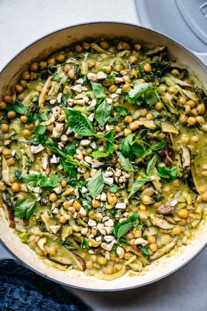 close up overhead of vegan chickpea green curry with Thai basil and cilantro garnish