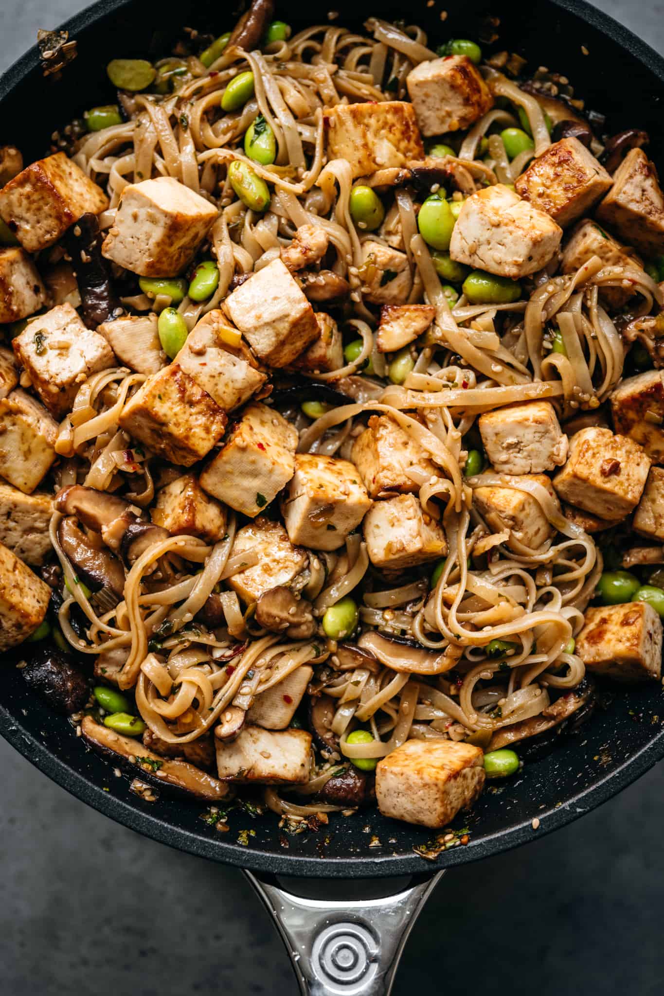 close up view of vegan rice noodles with crispy tofu in a skillet