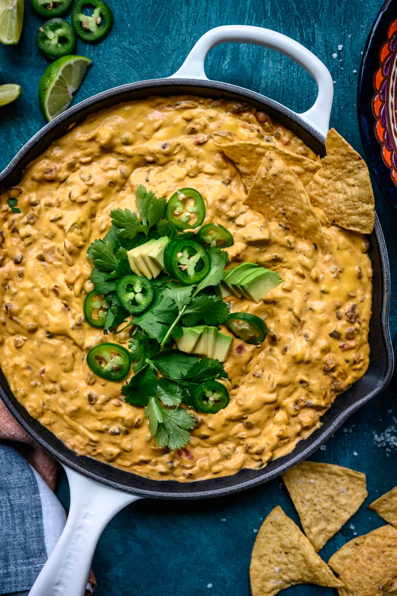close up overhead view of vegan chile con queso dip with tortilla chips in skillet