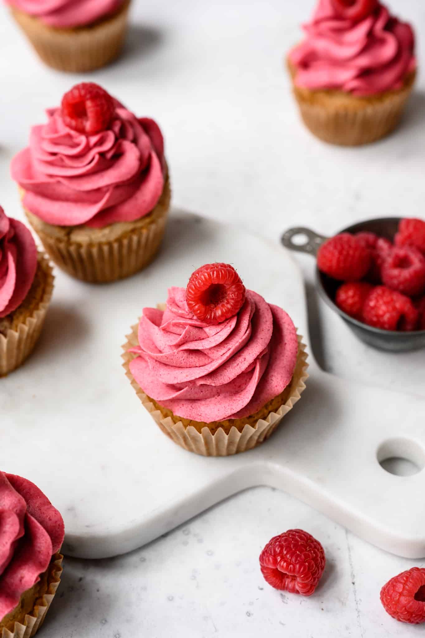 side view of raspberry almond cupcakes on white background