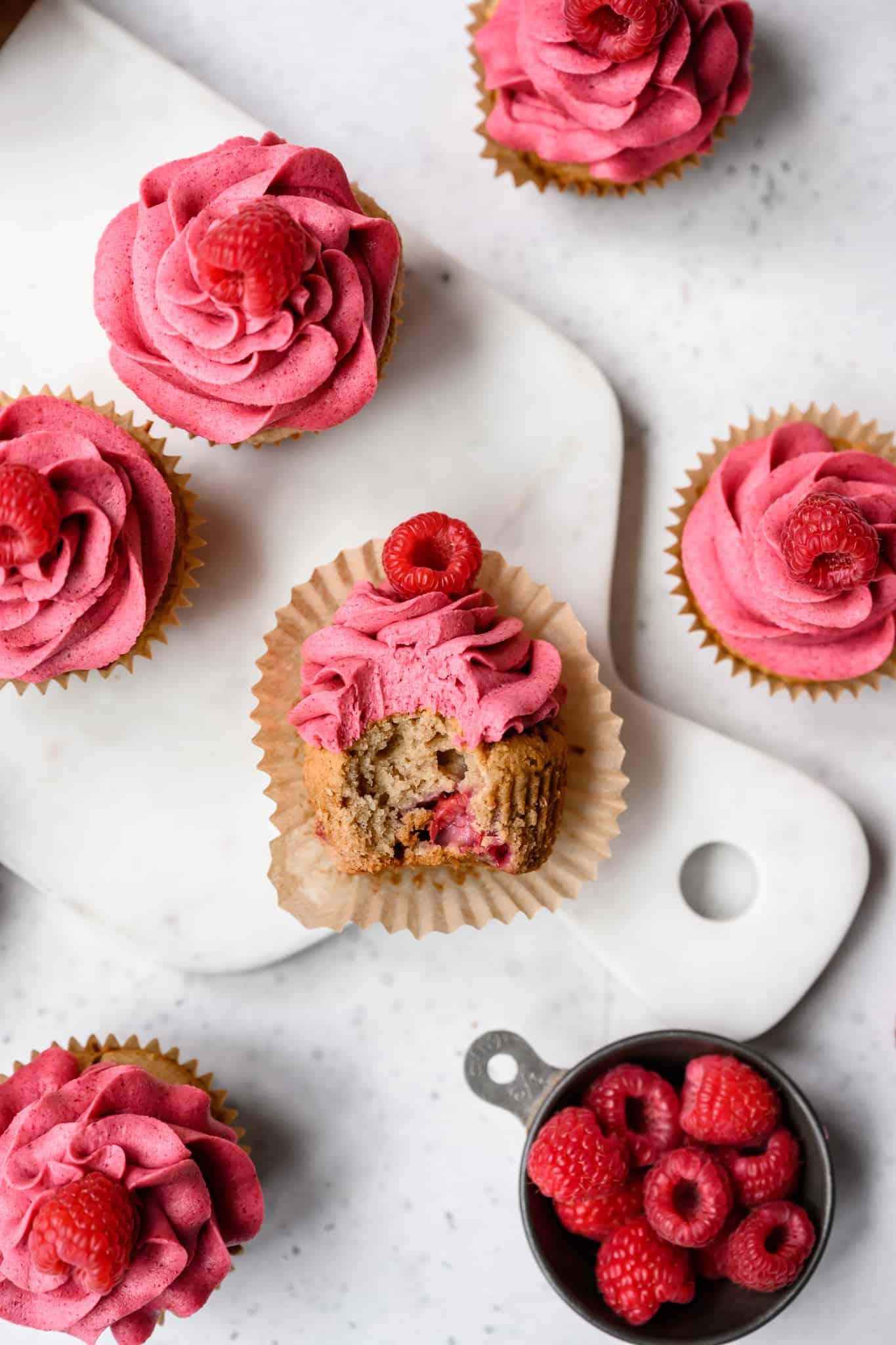 side view of raspberry almond cupcake with bite taken out