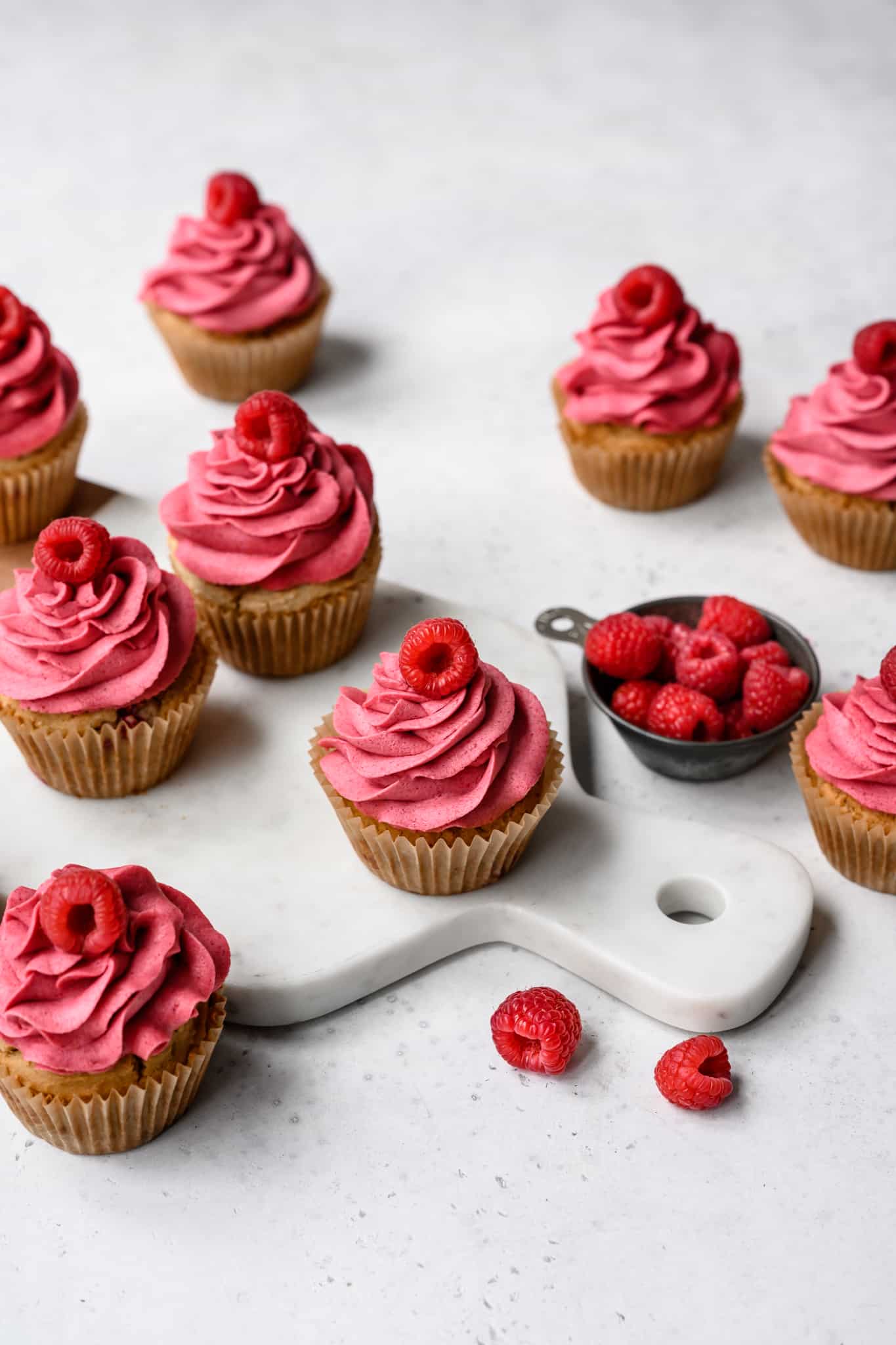 side view of raspberry almond cupcakes on white background