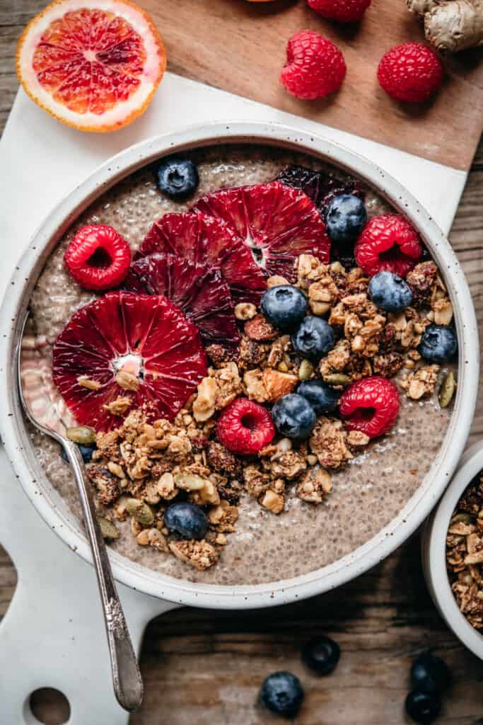 close up overhead view of chai chia pudding in white ceramic bowl with berries and granola