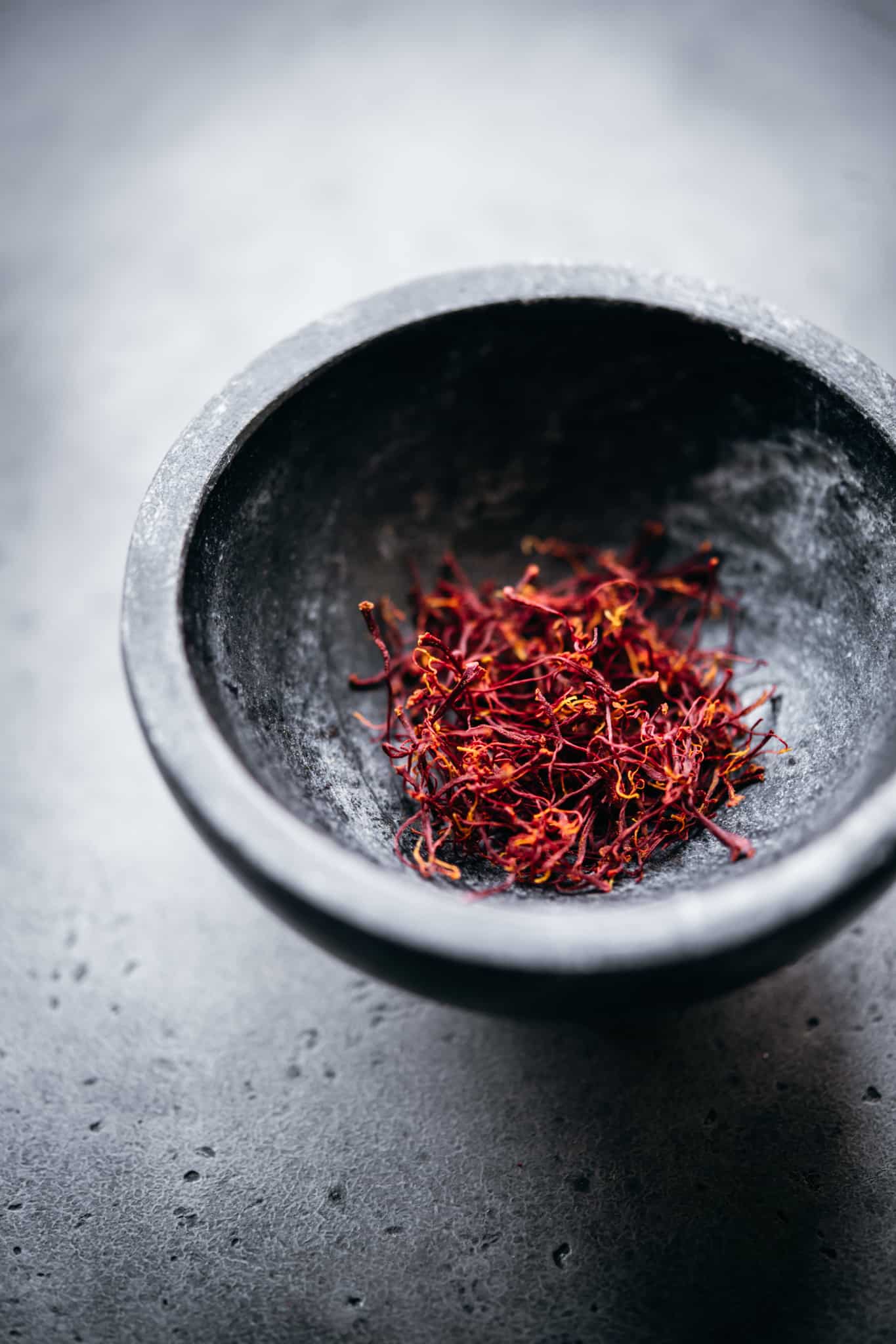 Close up view of saffron threads in a small black bowl