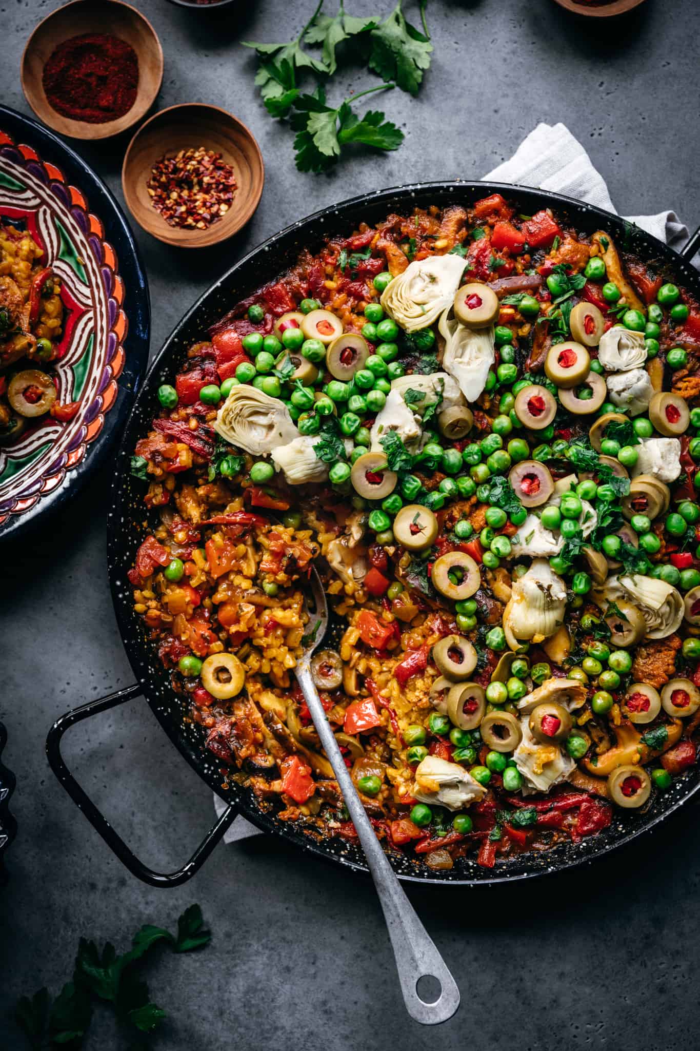 overhead view of vegan paella with peas, vegan chorizo, artichokes and olives