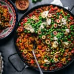 Vegan paella from above with olives and peas on top.