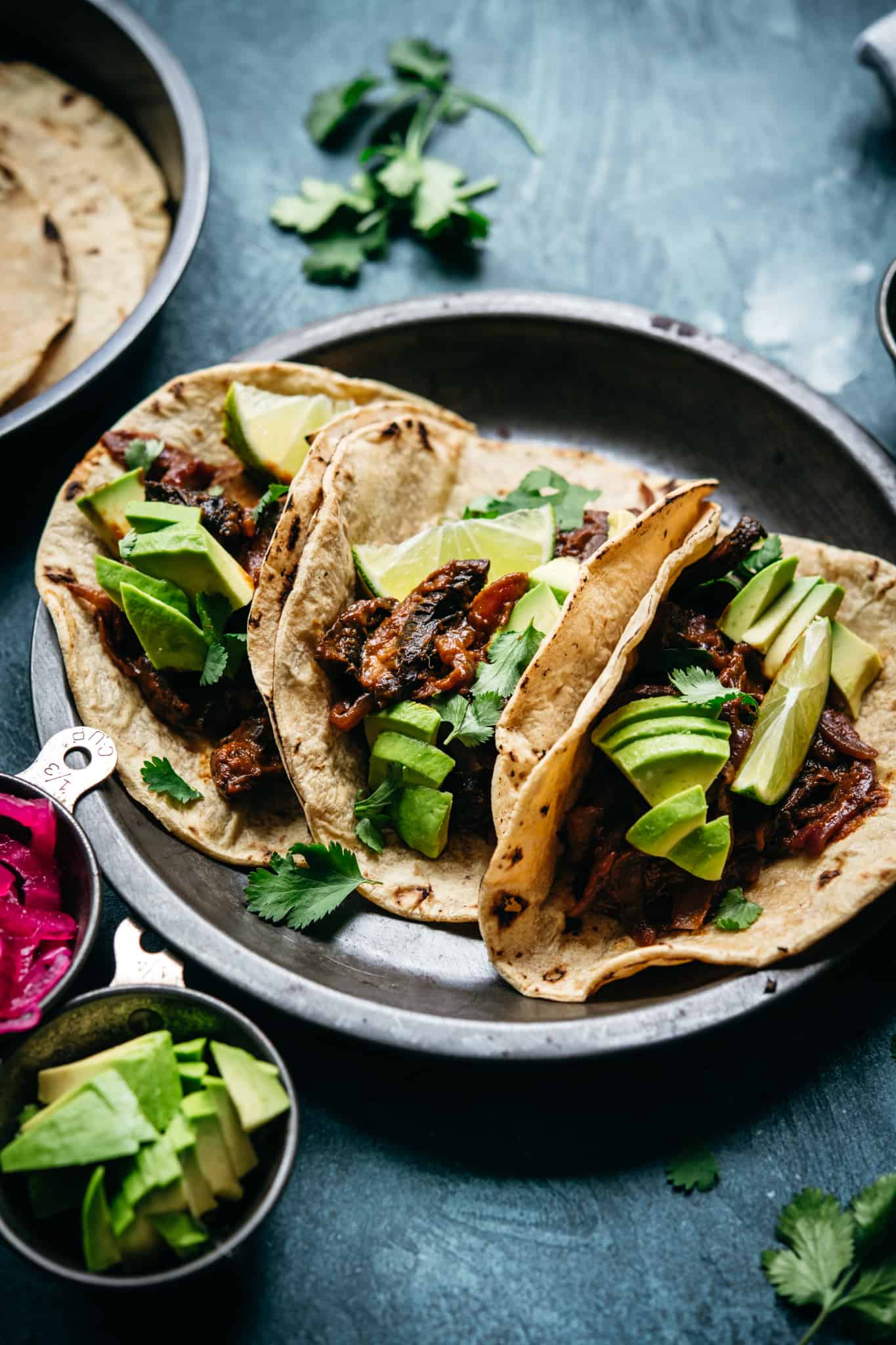 side view of vegan mushroom al pastor tacos in charred tortillas with avocado