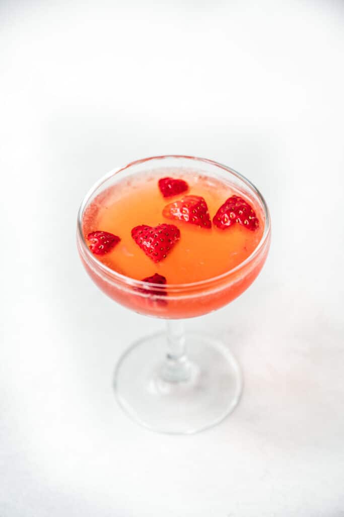 side view of valentine's day cocktail garnished with strawberry hearts