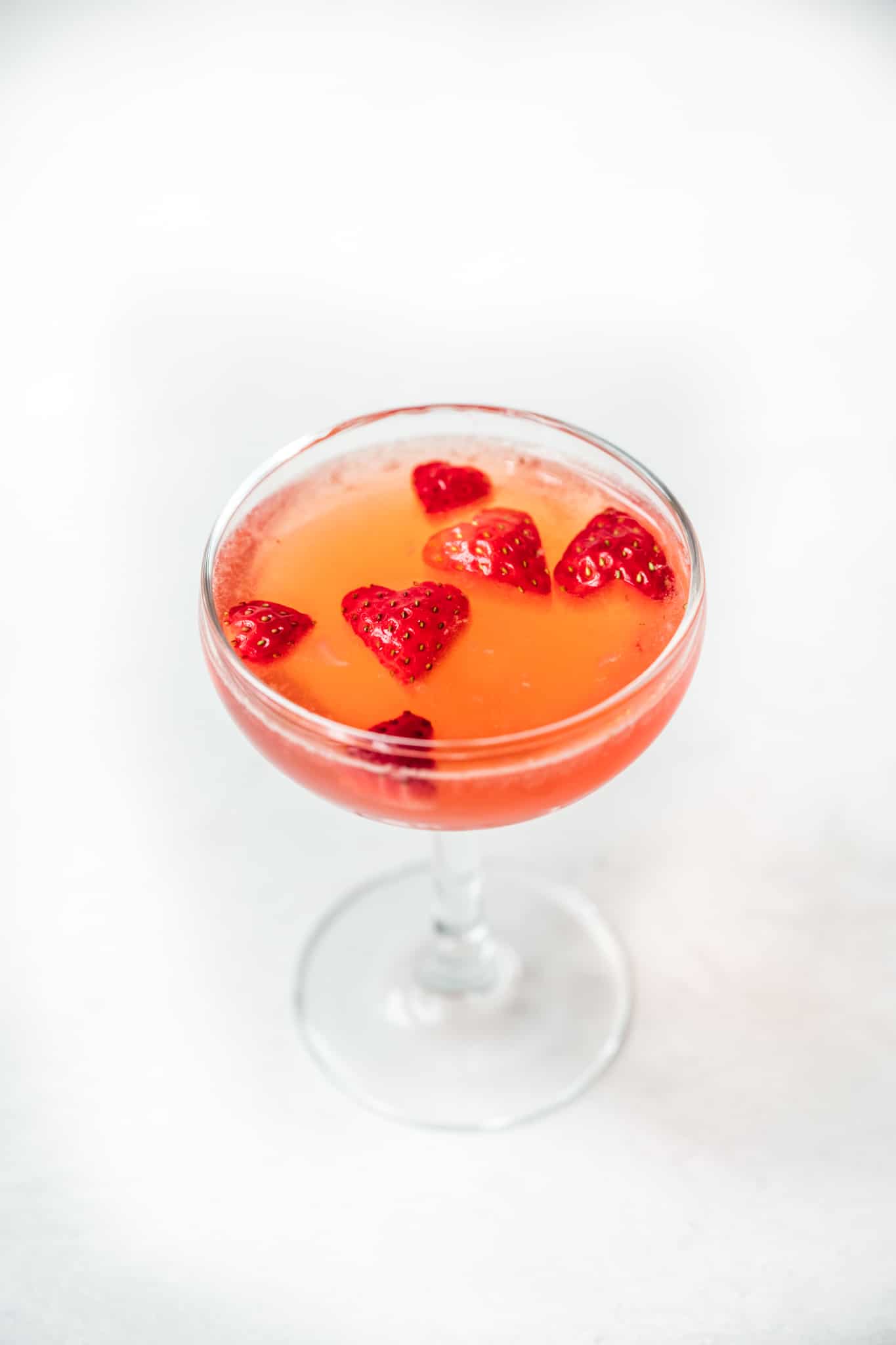 side view of valentine's day cocktail garnished with strawberry hearts