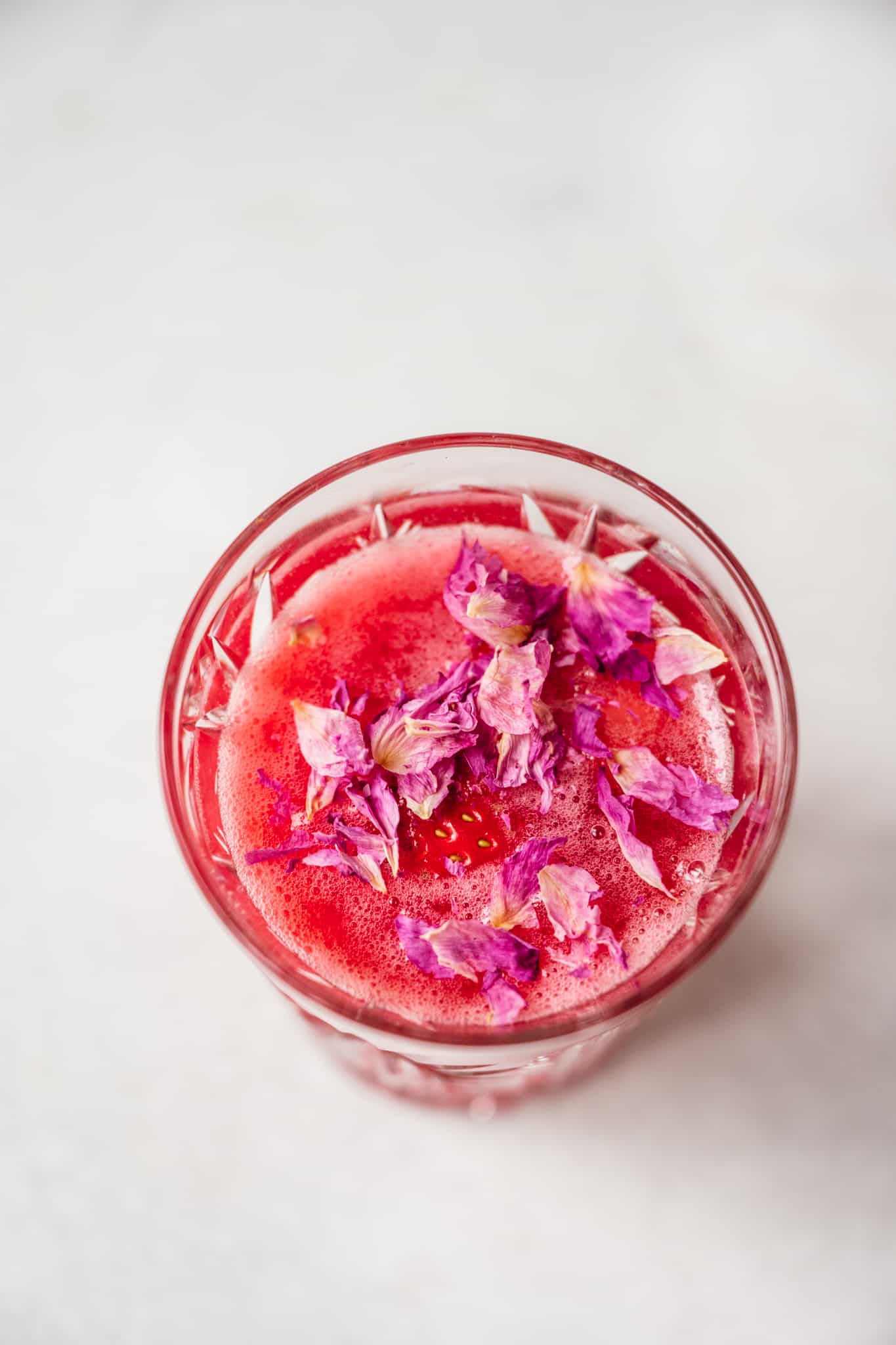 close up view of nonalcoholic pink drink with rose petals