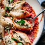 Stuffed pasta shells seen from above with a spoon lifting one out of the pot.
