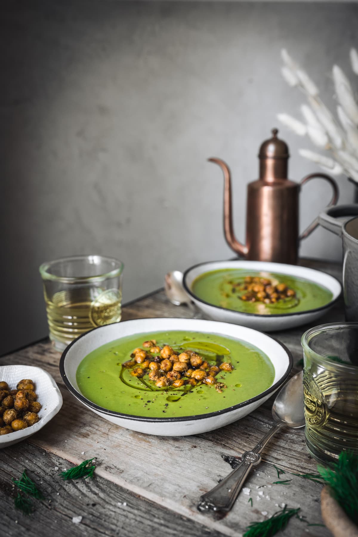 side view of vegan broccoli potato soup in a white bowl on wood table