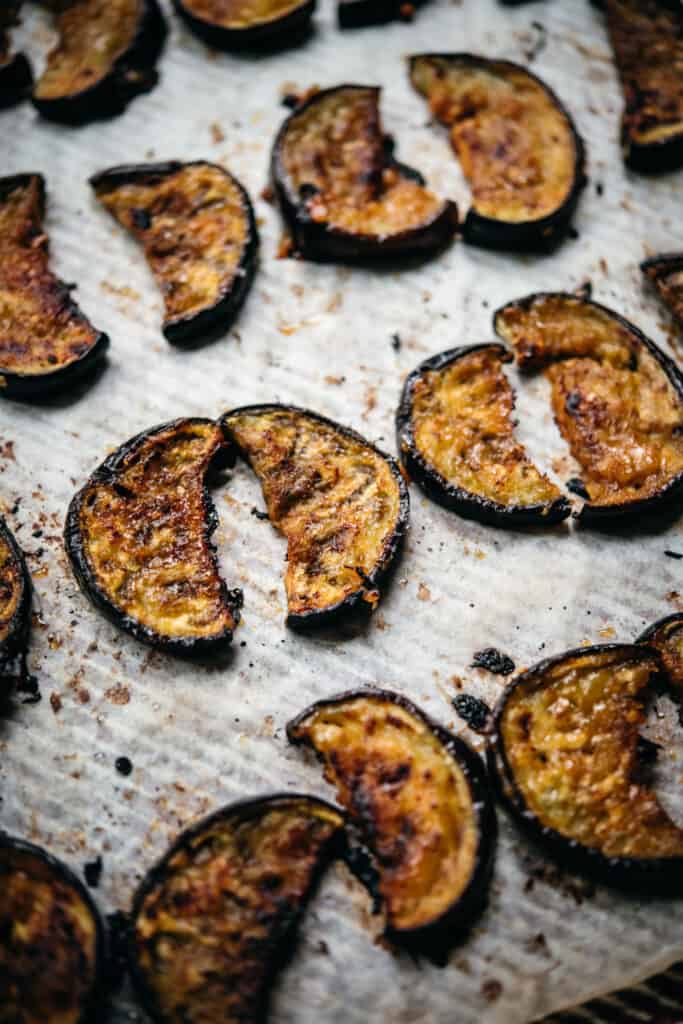 close up view of miso glazed oven roasted eggplant slices on sheet pan