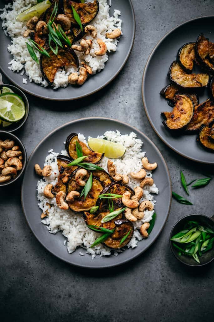 overhead view of oven roasted eggplant slices over rice with cashews and scallions
