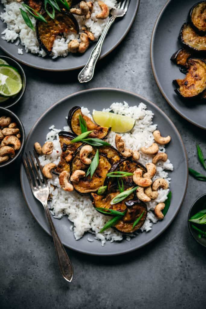 overhead view of oven roasted eggplant slices over rice with cashews and scallions