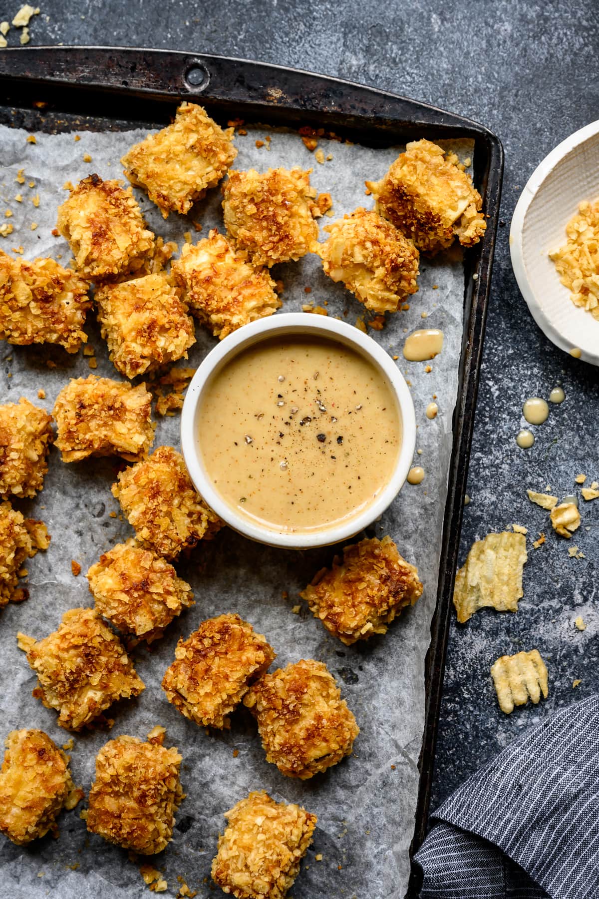 overhead view of crispy baked tofu nuggets on sheet pan with bowl of honey mustard 