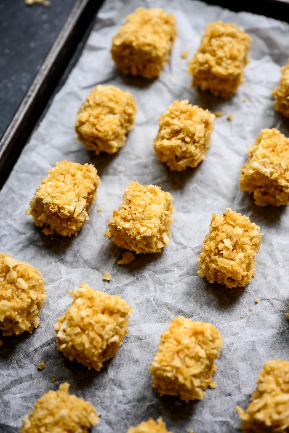 close up side view of baked tofu nuggets on sheet pan before baking