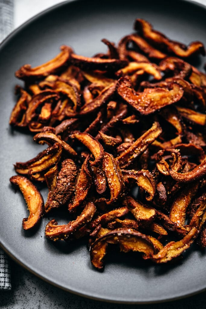 close up side view of fried shiitake mushroom bacon on plate