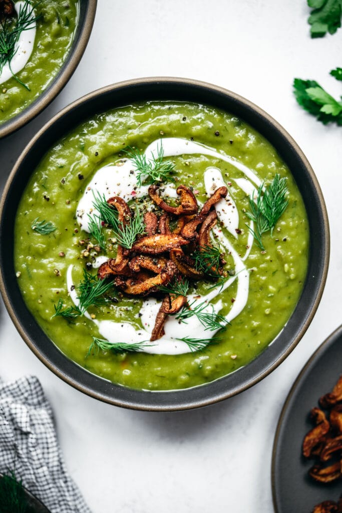 close up overhead view of vegan split pea soup topped with sour cream, mushroom bacon and dill