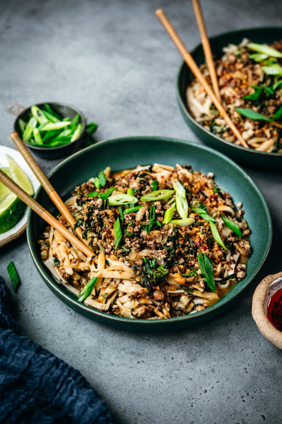 side view of vegan dan dan noodles in blue bowl with chopsticks