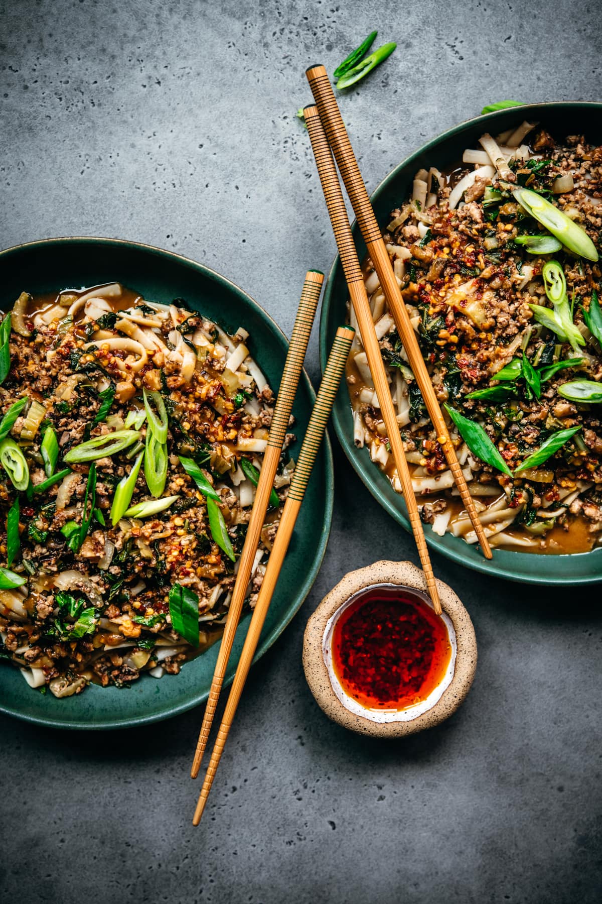 overhead view of two bowls of vegan dan dan noodles with chili oil and chopsticks