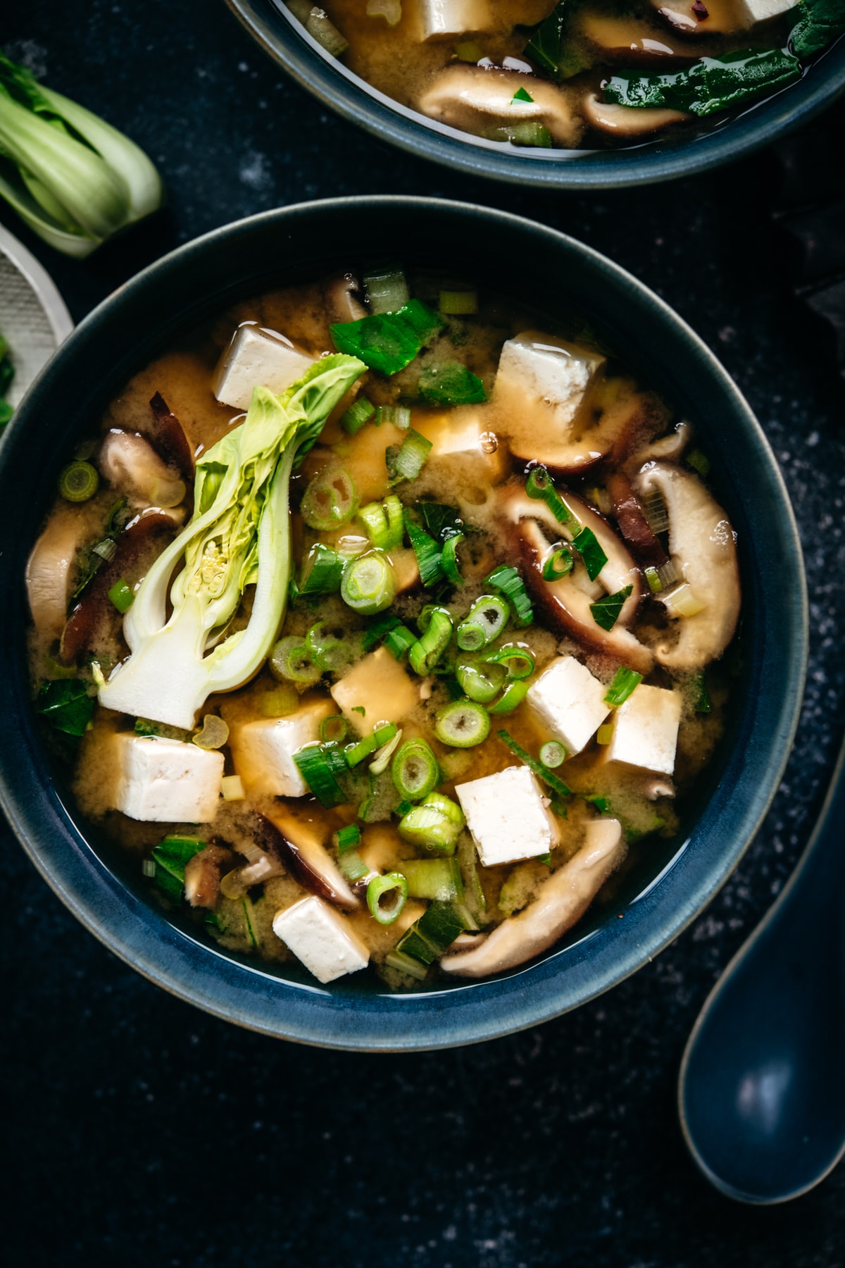 close up overhead view of vegan miso soup with tofu, mushrooms and scallions in a bowl