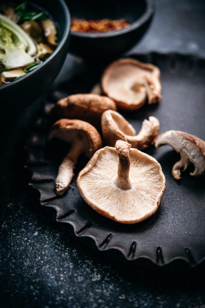 close up side view of shiitake mushroom on black plate