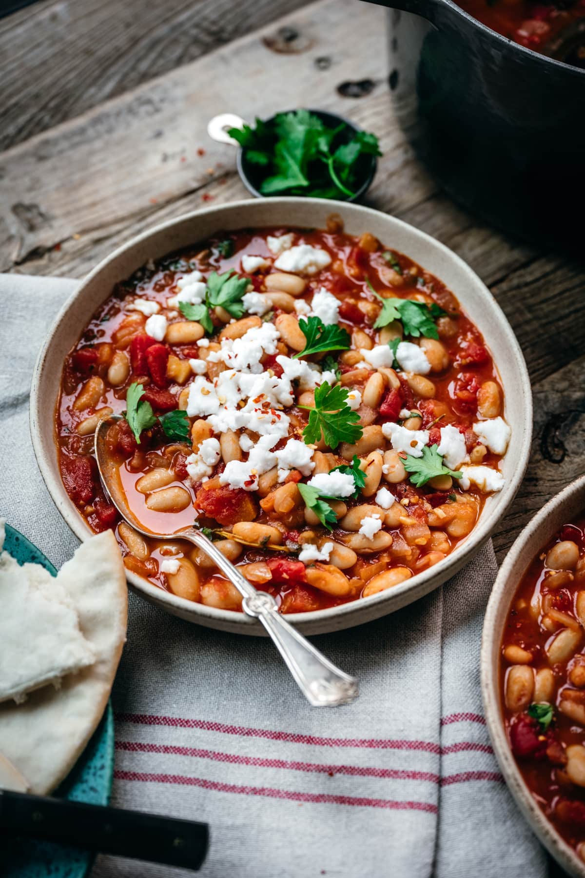 backlit side view of tomato white bean stew on a wood table