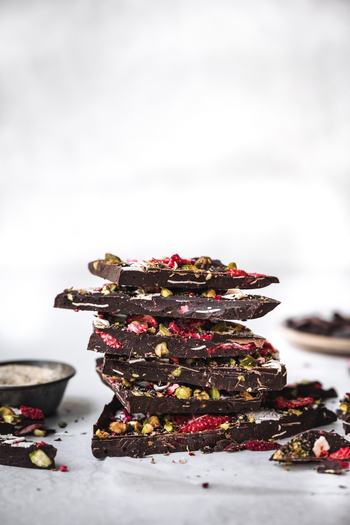 side view of stack of dark chocolate bark with strawberries and pistachios