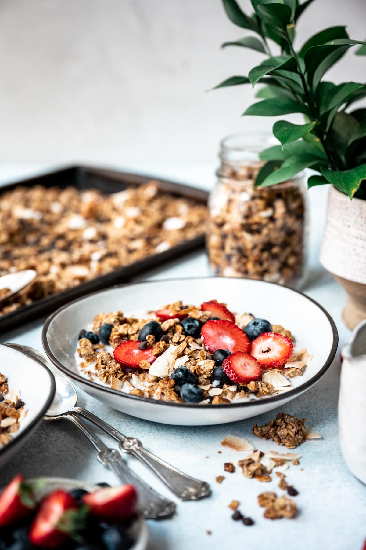 side view of banana bread granola in bowl with milk, strawberries and blueberries 