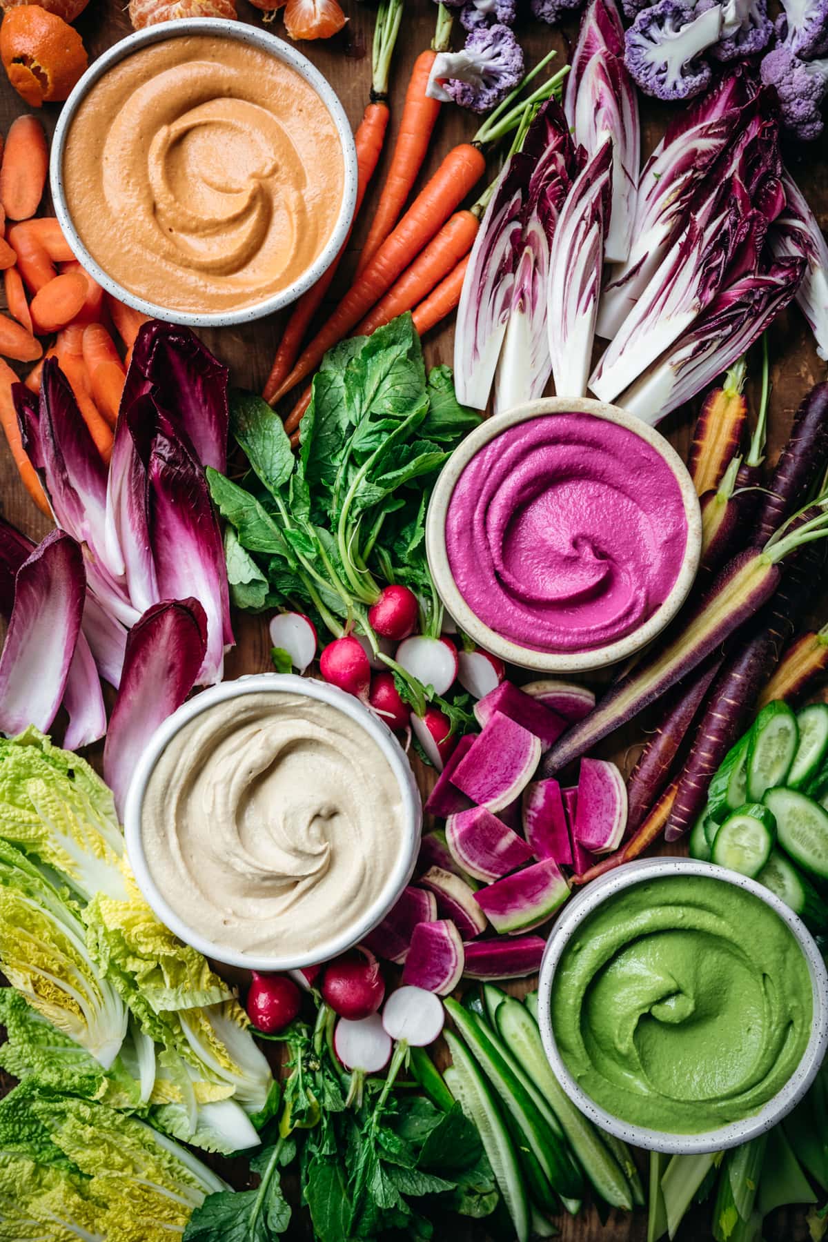 overhead view of homemade hummus 4 ways with colorful vegetables on a platter