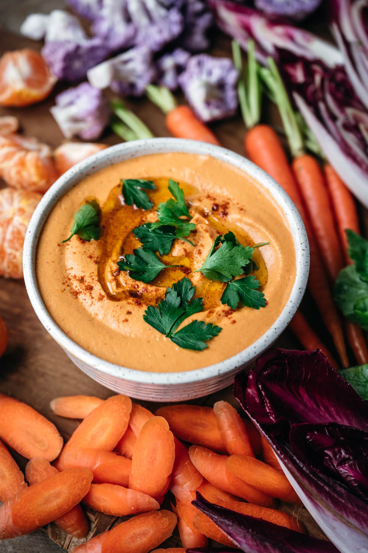 close up view of roasted red pepper hummus with parsley and harissa