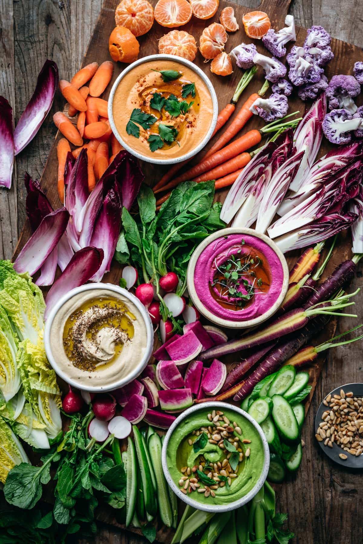 overhead view of homemade hummus 4 ways with colorful vegetables on a platter