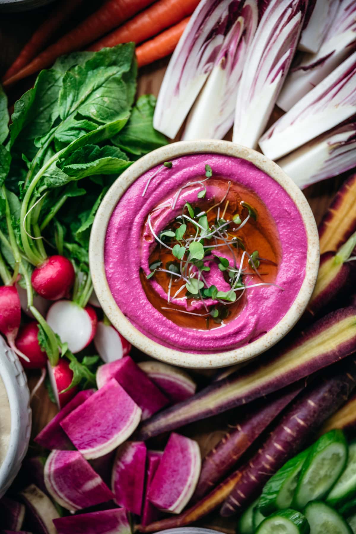 overhead view of pickled beet hummus in a bowl with colorful fresh vegetables