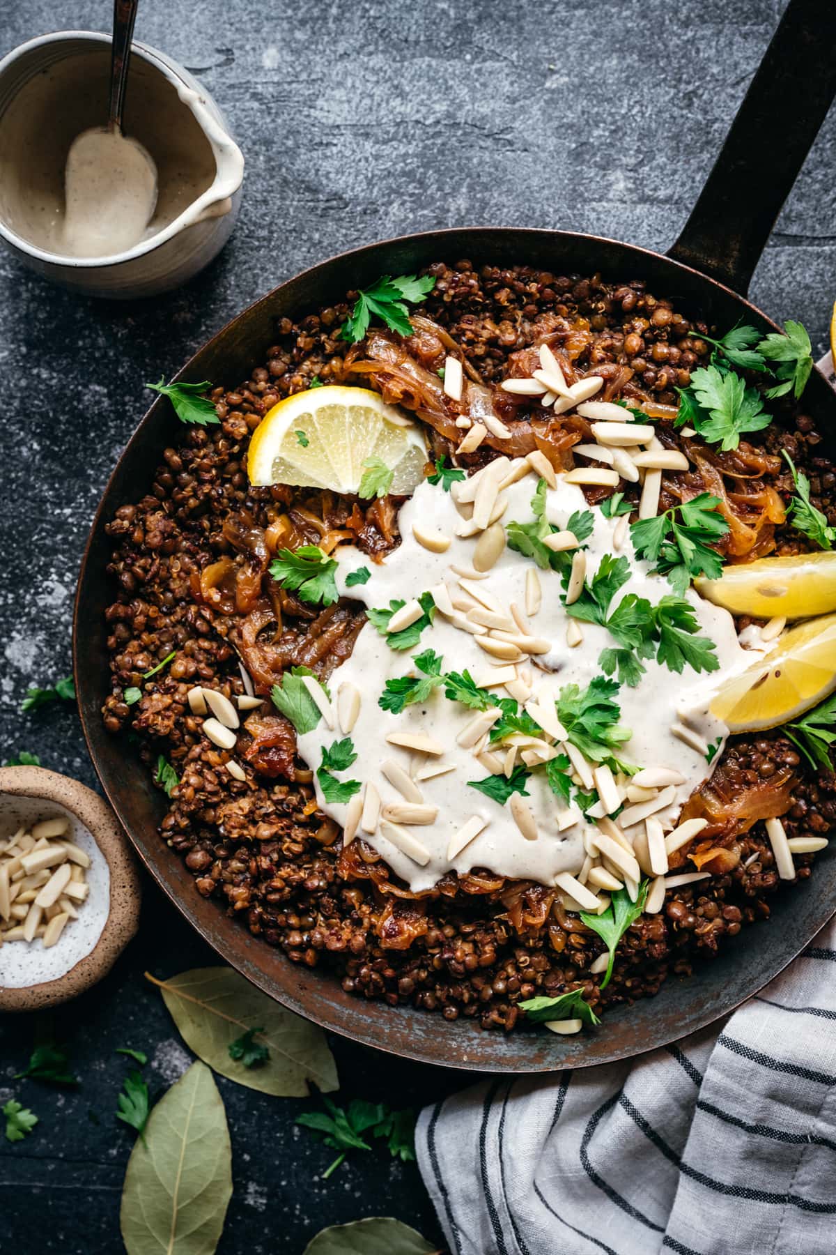 overhead view of vegan mujarada in a pan with tahini yogurt sauce