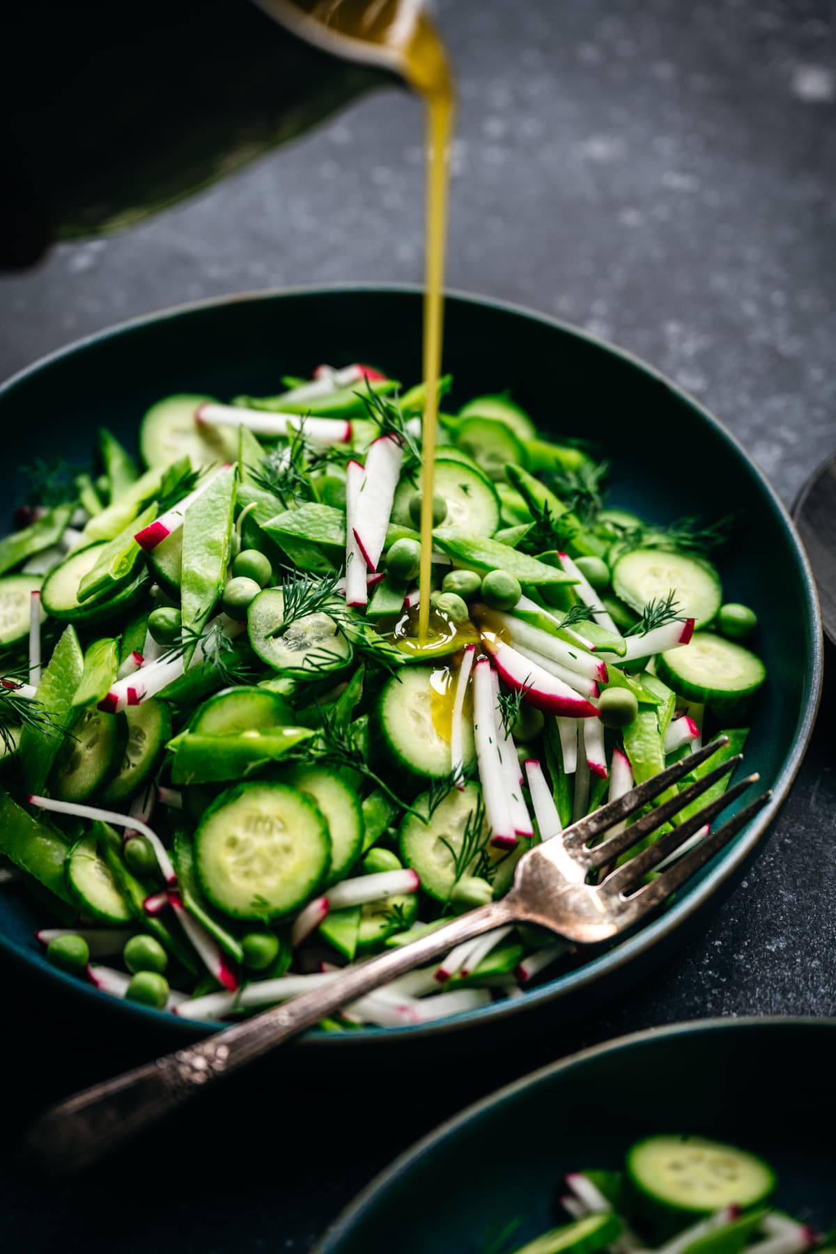 pouring lemon vinaigrette onto fresh pea salad