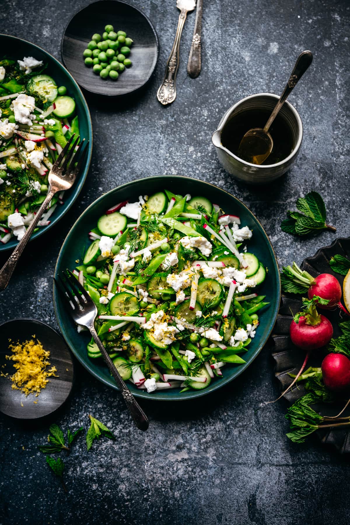 Overhead view of snow pea salad with radishes, cucumber and vegan feta in blue bowl