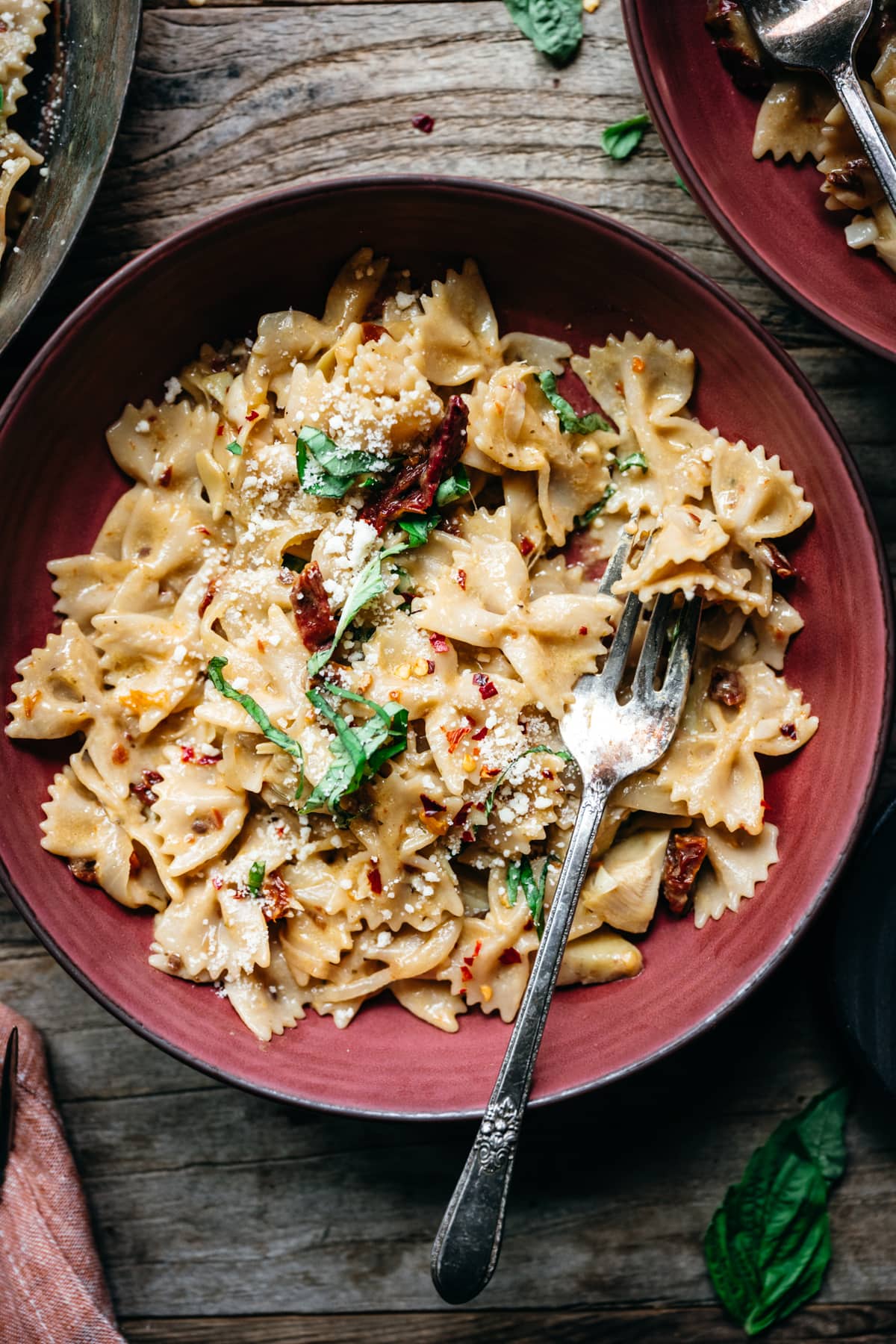 close up overhead view of vegan sun-dried tomato pasta in red bowl