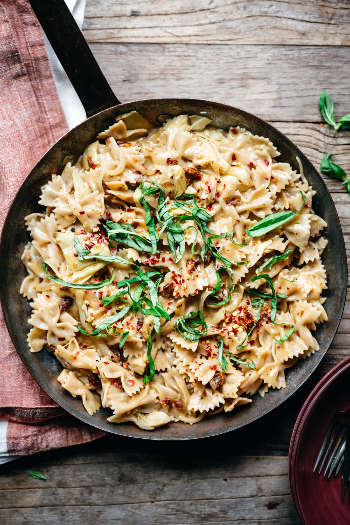 overhead view of vegan sun-dried tomato pasta with basil and red pepper flakes in pan