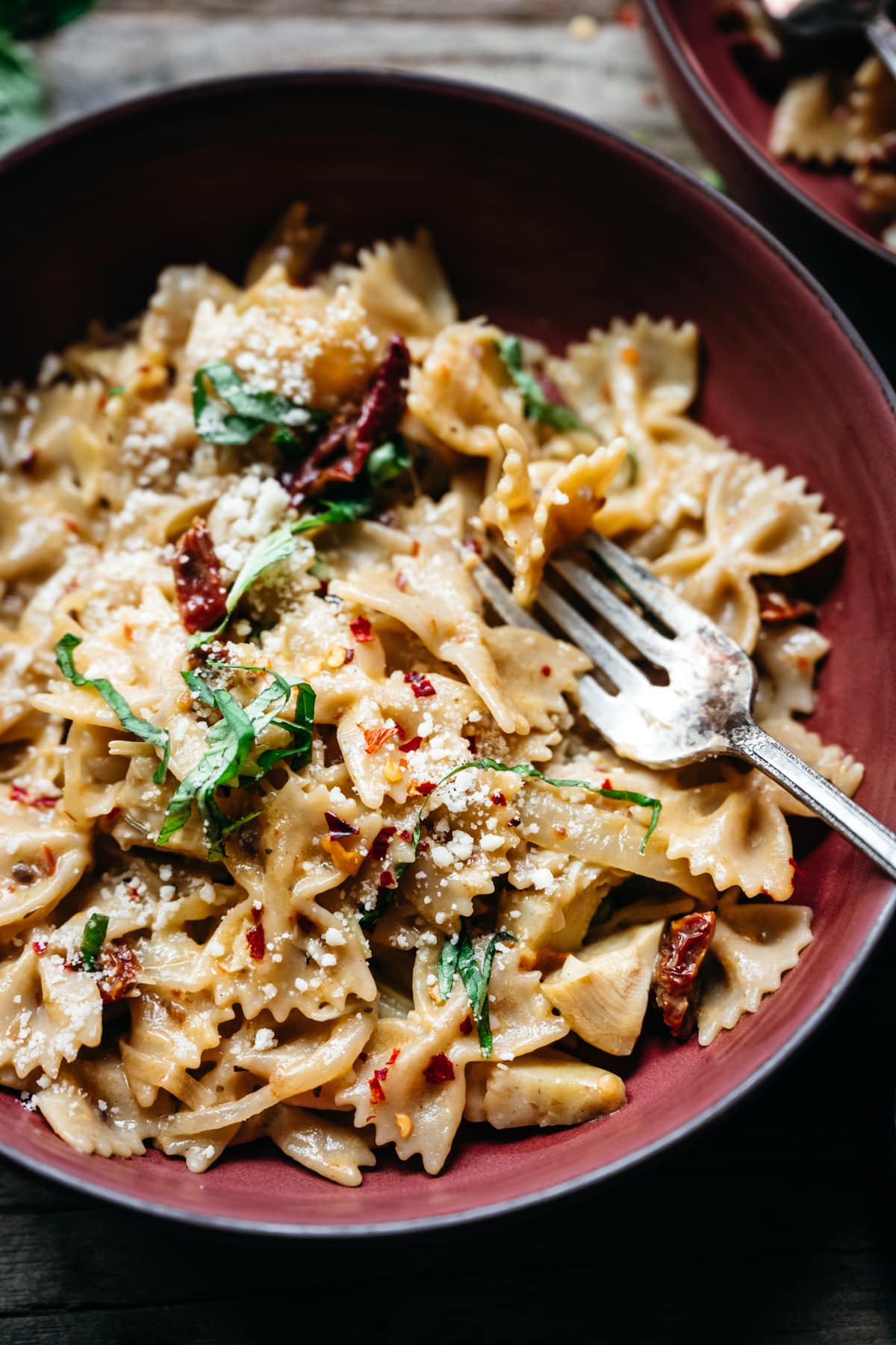 close up overhead view of vegan sun-dried tomato pasta in red bowl