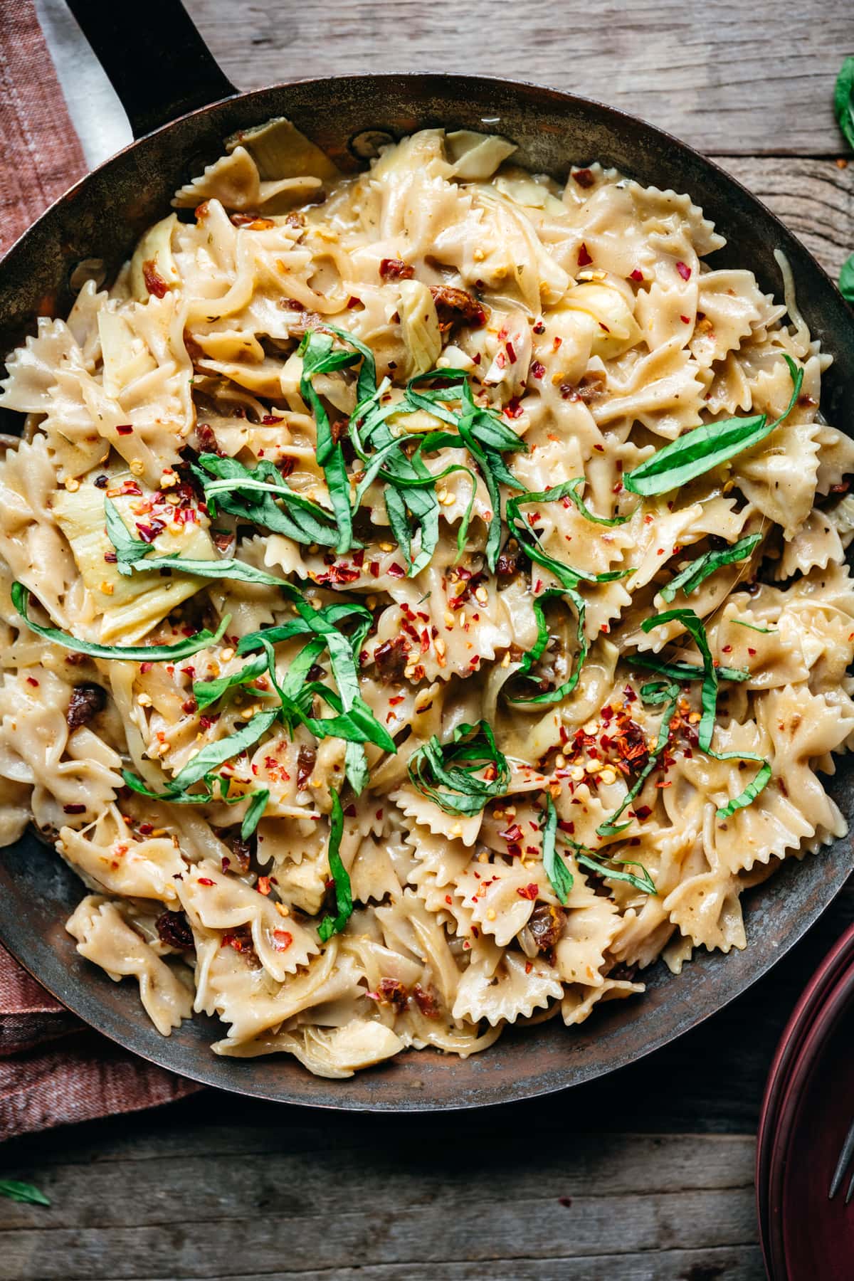 overhead view of vegan sun-dried tomato pasta with basil and red pepper flakes in pan